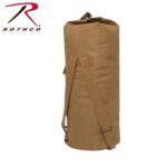 A cylindrical tan duffel bag stands upright featuring a rolled top and two shoulder straps secured to its side suitable for carrying items during travel or outdoor activities