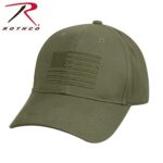 A green cap with an embroidered American flag design on the front is positioned at an angle showcasing its curved brim and textured fabric in a neutral background.