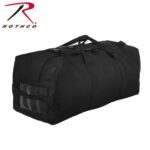 A black duffel bag sits upright featuring sturdy handles and buckled straps with a transparent section on one side for identification in a neutral background.