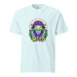 A light blue t-shirt features a colorful alien character holding cannabis leaves and smoking a joint surrounded by the word WEED in vibrant letters against a bold background.