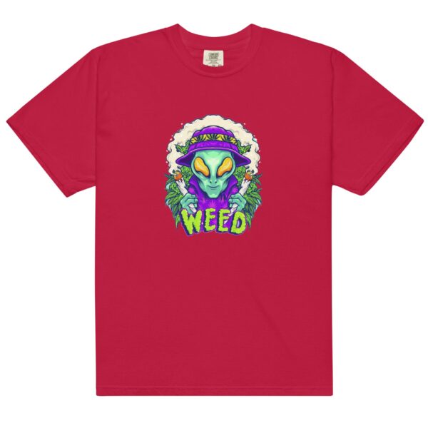 A red t-shirt features a graphic of a green alien with large eyes holding a joint surrounded by cannabis leaves and smoke with the word WEED prominently displayed below the alien.