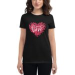 A black t-shirt features a heart made of red rose petals with the word love in elegant white script at the center being worn by a woman with medium-length hair.