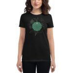 A woman wears a black t-shirt featuring a green graphic with floral elements and the text Life's like a cup of tea surrounded by nature-themed designs in a casual setting.