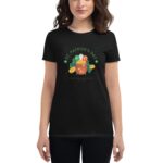 A person wears a black t-shirt featuring a colorful illustration of a pot of gold surrounded by clovers and balloons celebrating St. Patrick's Day with text wishing luck at the end of the rainbow.