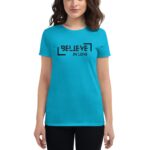 A woman wears a bright turquoise t-shirt featuring the text BELIEVE IN LOVE in bold black letters against a simple background  demonstrating a positive and uplifting message on casual apparel.