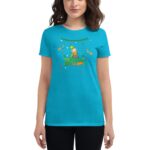 A woman wears a bright turquoise t-shirt featuring a cartoon character celebrating St Patrick's Day surrounded by festive elements like shamrocks and confetti in a cheerful context.