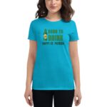 A woman wears a bright turquoise t-shirt with the text Born to Drink Happy St. Patrick alongside an image of a beer bottle  suggesting a festive St. Patrick's Day theme.