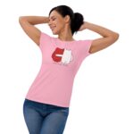 A woman wearing a pink t-shirt smiles while stretching her arms behind her head the shirt features a graphic design with red and white characters and the text FOREVER MINE