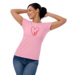 A woman in a pink t-shirt with a red heart design and the word love is playfully stretching with a smile in a bright  neutral background environment.