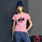 A young woman stands against a textured backdrop wearing a pink t-shirt with the word "LOVE" and floral designs. She has long hair and is wearing a dark beanie.