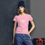 A young woman in a pink t-shirt with white text stands confidently against a dark wall holding her hand on her hip while wearing a dark beanie and blue jeans.