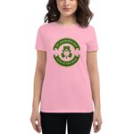 A woman wears a pink t-shirt featuring a circular graphic with a leprechaun and the text ST. PATRICK'S DAY LUCK OF THE IRISH in green set against a simple backdrop.