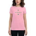 A woman wears a pink t-shirt featuring the text "JUST WANTED TO SAY MAKE YOUR OWN LUCK" with green clover designs  standing against a neutral background.