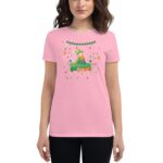 A woman in a pink t-shirt is wearing a festive design featuring a cartoon character celebrating St. Patrick's Day surrounded by colorful stars and decorations.