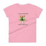 A pink t-shirt features three cheerful characters in green outfits celebrating St. Patrick's Day accompanied by text wishing good fortune and a happy holiday amidst festive decorations.