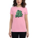 A person is wearing a pink t-shirt featuring the text "Enjoy Every Moment" in a playful green font  standing against a plain background. The shirt conveys a cheerful message.