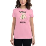A person wears a pink t-shirt featuring a graphic of a character holding a green bottle with text above and below that reads Happy St. Patrick Wine because adulting is hard.