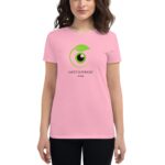 A woman wears a pink t-shirt featuring a circular green and black graphic with the text SAINT PATRICKS 2024 underneath  standing against a neutral background.