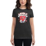 A person wears a dark t-shirt featuring a colorful graphic of a happy heart character with the text "LOVELY PERSON" above it in a playful font  set against a neutral background.