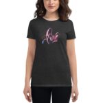 A woman is wearing a dark t-shirt with colorful text that says love surrounded by a festive design  standing against a neutral background which emphasizes the shirt's design.