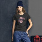 A young woman stands against a dark gray wall wearing a black t-shirt featuring a floral design with the word "LOVE" in colorful letters  paired with blue jeans and a navy beanie.