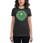 A woman wears a dark t-shirt featuring a festive design with clovers and the text Happy St. Patrick's Day highlighting the holiday's celebration in a casual setting.