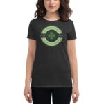 A woman is wearing a dark gray t-shirt featuring a green design with a shamrock and text celebrating St. Patrick's Day love luck and luck of the Irish.
