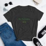 A dark gray t-shirt displays the text "HAPPY St. Patrick's DAY" in green  placed on a flat surface alongside blue jeans  black sneakers  and sunglasses  suggesting a casual outfit for celebration.