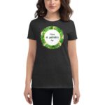 A woman wears a dark t-shirt featuring a circular design with green and gold accents that reads Happy st. patrick's day surrounded by shamrock leaves