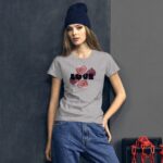 A young woman stands confidently wearing a grey t-shirt adorned with the word LOVE surrounded by floral designs while dressed in casual jeans and a dark beanie against a muted backdrop.