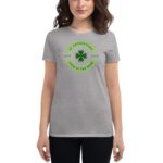 A woman wearing a gray t-shirt displays a green graphic featuring a shamrock and text celebrating St. Patrick's Day embodying themes of love and luck.