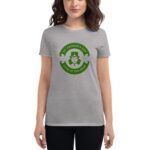 A woman wears a gray t-shirt featuring a circular green design with a leprechaun illustration and the text ST. PATRICK'S DAY LUCK OF THE IRISH in celebration of the holiday.