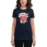 A woman wears a dark t-shirt featuring a cartoon heart character hugging a blue object with the text "LOVELY PERSON" above it in a playful design.