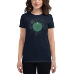 A woman is wearing a dark t-shirt featuring a green graphic with the text Life's like a cup of tea surrounded by illustrations of tea leaves and flowers in a simple design.