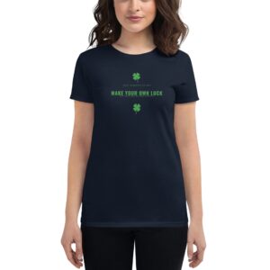 A woman is wearing a dark t-shirt with green text that reads JUST WANTED TO SAY MAKE YOUR OWN LUCK accompanied by two small green shamrocks in a neutral background.