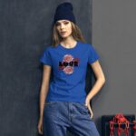 A young woman stands against a textured gray wall wearing a blue t-shirt with "LOVE" and floral graphics while dressed in loose jeans and a dark beanie.