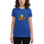 A woman wears a blue t-shirt featuring a graphic of a pot decorated with gold coins and colorful balloons with text that says ST. PATRICK'S DAY in a festive design.