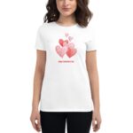 A woman wears a white t-shirt decorated with various heart shapes in pink tones and the text Happy Valentine’s Day displayed prominently on the front.