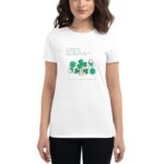 A woman wearing a white t-shirt with a green print featuring shamrocks and a quote celebrates St. Patrick's Day while posing against a neutral background.