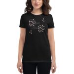 A woman is wearing a black t-shirt featuring a design with the text "Love Always" surrounded by circles and diamond shapes in pink and white  set against a plain background.