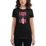 A woman is wearing a black t-shirt displaying the word "LOVE" three times in varying colors and fonts  standing in a neutral environment.