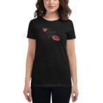 A black t-shirt is worn by a woman with short wavy hair featuring a graphic print of hearts and the words love you along with pink lip prints in a casual setting.