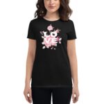 A woman wears a black t-shirt featuring the word "LOVE" in white  surrounded by pink flowers. She stands confidently  showcasing the shirt's design in a casual setting.