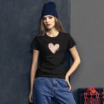 A young woman stands confidently  wearing a black t-shirt with a heart design and the text Happy Valentine's Day. She's in an industrial setting with gray walls and red chains.