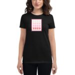 A woman in a black t-shirt stands  displaying a graphic design resembling a postage stamp with the text XOXO in various colors  against a neutral background.