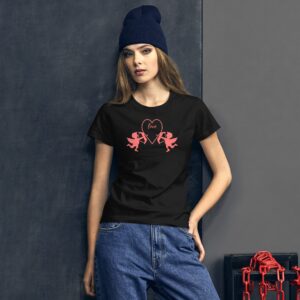 A young woman poses wearing a black t-shirt featuring pink Cupid designs and the word love surrounded by a heart in front of a textured gray wall with red chains nearby.