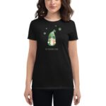 A woman is wearing a black t-shirt with a cartoon gnome graphic and green clovers above it in celebration of St. Patrick's Day with text below the gnome reading St. Patrick's Day