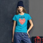 A young woman wears a bright blue t-shirt featuring a red heart design with fingerprint patterns above the word LOVE while standing against a dark textured wall and a red chain backdrop.