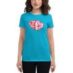 A woman wearing a bright turquoise t-shirt with a stylized graphic of two overlapping heart-shaped boxes filled with chocolates is standing confidently against a neutral background.