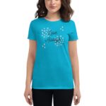 A woman is wearing a bright turquoise t-shirt with the text "Love Always" printed in black  surrounded by decorative elements  while standing against a plain white background.